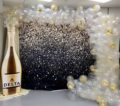 a bottle of delta champagne next to balloons in front of a black and white backdrop