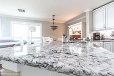 a kitchen with marble counter tops and white cabinets