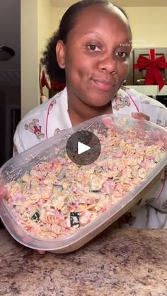 a woman in uniform holding up a plastic container filled with pasta and meat mixtures