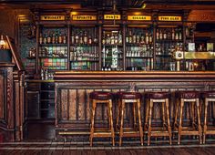 the bar has four stools and several bottles on it