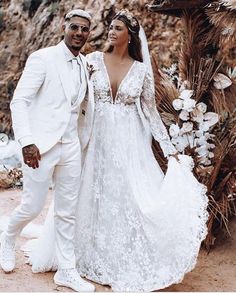 a bride and groom standing next to each other in front of an arch decorated with flowers