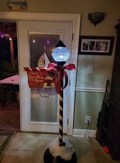 a christmas decoration on top of a pole in front of a door with a light