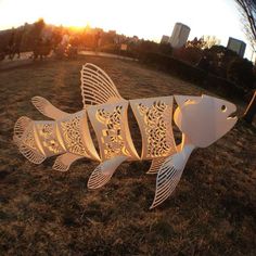 three white fish sculptures sitting on top of a grass covered field