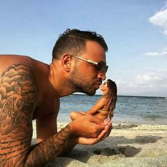 a man on the beach kissing a woman's face