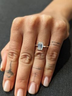 a woman's hand with a diamond ring on her left hand and tattoos on the other hand