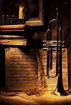 an old trumpet sitting on top of music sheets in front of a painting and candle