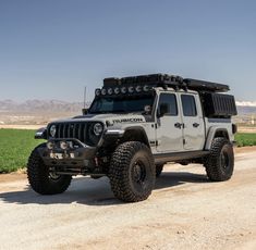 a white jeep is parked on the side of a dirt road