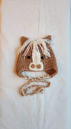 a crocheted brown horse hat on top of a white sheet