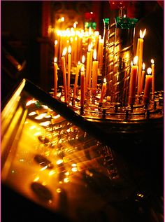 many candles are lit in the dark with bright lights around them and on top of a table