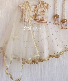 ✨ If you are looking for something for your little girl to wear, you will love this net white lehenga choli. ✨ The Jasmine Lehenga has an intricate design with an alluring pattern embroidery on the blouse. This is an excellent piece of cloth for any child who wants to look radiant. This is a piece of clothing made by Indian designers and craftsmen. It is a beautiful, embellished, and flowing piece of clothing. It is a perfect piece of clothing for any child looking to have a traditional Indian look. This net white lehenga choli for kids is the perfect attire for eid day. ✨ The Lehenga Choli has a small matching dupatta that can be worn in a variety of ways. The White Lehenga Choli Dupatta is a must-have for your little girl. The dupatta is the right length that goes well with the skirt. Th White Gota Work Sets For Celebration, White Self-design Party Sets, White Dori Work Party Dress, Festive Anarkali Frock For Wedding, Navratri Celebration Gold Dress, Fitted Wedding Frock For Festive Season, Bollywood Style Frock For Navratri Wedding, White Dress With Zari Work For Celebration, White Choli For Eid Celebration