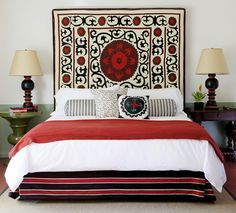 a bed with two lamps on either side of it and a red blanket over the headboard