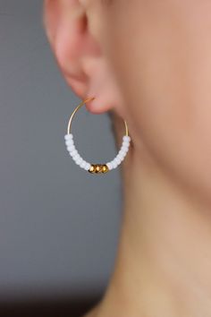 Dainty hoop earrings with white tiny glass seed beads, gold tone stainless steel beads and gold tone stainless steel round hoop earrings. Earring hooks are from nickel free and lead free metal. Perfect jewelry for everyday wear or a great gift for someone special! Diameter of hoops is 25 mm Other earrings of my shop you can see here: https://www.etsy.com/shop/NaTavelli?section_id=13757927 Thanks for visit. Dainty Hoop Earrings, Beaded Hoop Earrings, Beaded Hoops, White Earrings, Delicate Earrings, Simple Earrings, Circle Earrings, Minimalist Earrings, Jewelry Earrings Hoops