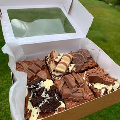 a box filled with lots of different types of desserts on top of green grass