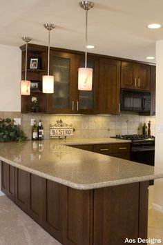 a kitchen with brown cabinets and marble counter tops, lights above the island in front of the sink