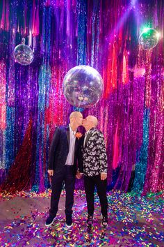 two people standing in front of balloons and streamers