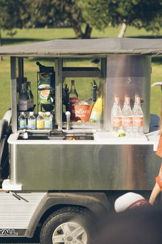 a woman standing next to a silver cart filled with drinks