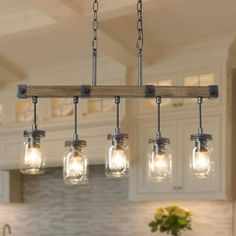 a kitchen island light with mason jars hanging from it's center and four lights on each side