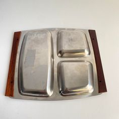 an empty metal tray with three compartments on top of it and a wooden board in the middle