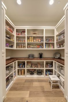 an organized pantry with white shelves and wooden flooring