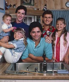 a group of people standing in front of a kitchen sink with two children and one adult