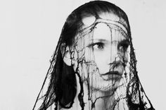 a black and white photo of a woman's face covered in hair with strings