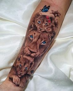 a tattoo with lions and butterflies on it's arm, which has blue eyes