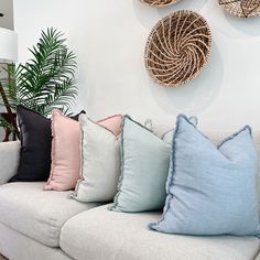 a couch with several pillows on it in front of a wall mounted wicker basket