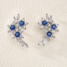 Amp up your stylish look with this stunning pair of earrings. This pair exudes an endearing design, making it an alluring choice. The adornment of a fine-cut sapphire zircon stone adds to its delightful appeal. Elegant Design: Elegant and luxurious flower shape earrings and inlaid blue sapphire make these earrings perfect for any formal occasion. High-Quality Material: Made with high-quality copper adorned with stunning blue zircon gems, these earrings are durable and long-lasting. Versatile: Suitable for a variety of occasions, including parties, weddings, prom, banquets, and more. Lightweight and comfortable: Lightweight and easy to wear. Adds a touch of sophistication to any outfit and comfortable to wear all day long. Luxury Flower-shaped Cubic Zirconia Jewelry, Luxury Cubic Zirconia Flower Earrings For Wedding, Luxury Formal Flower-shaped Earrings, Luxury Stone Earrings For Formal Occasions, Luxury Flower-shaped Jewelry With Cubic Zirconia, Luxury Designer Earrings For Formal Occasions, Luxury Blue Flower-shaped Earrings, Luxury Sapphire Elegant Earrings, Luxury Fine Jewelry Earrings For Formal Occasions