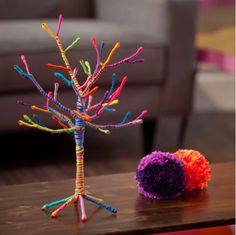 there is a small colorful tree next to a ball on the table in front of it