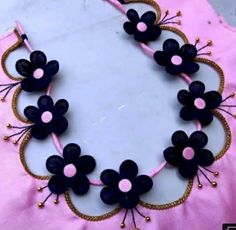 a pink and black necklace with flowers on it