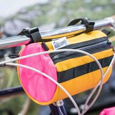 a yellow and black bag sitting on the back of a bicycle handlebar with pink linings