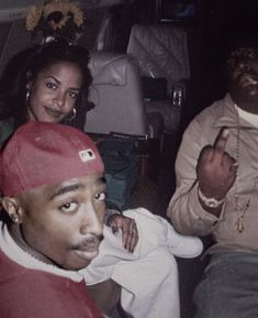 three people sitting in the back of a car with one person wearing a red hat