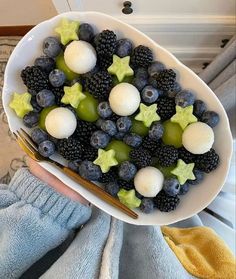 a white bowl filled with berries and other fruits on top of a table next to a blue towel