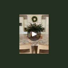 a table with chairs and a potted plant on it in the middle of a room