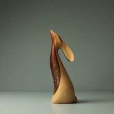 a wooden sculpture sitting on top of a white table next to a gray wall and floor