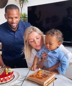 a man, woman and child standing in front of a cake with candles on it