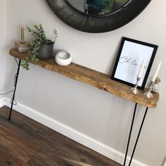 a wooden table topped with a mirror and plant on top of it next to a wall