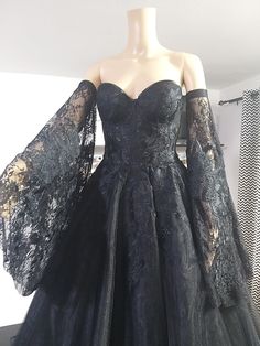 a mannequin wearing a black dress with lace sleeves