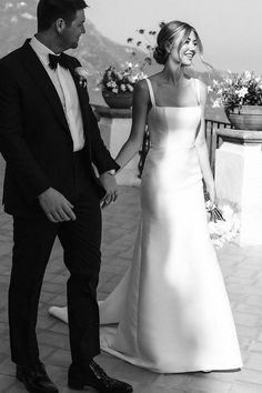 a bride and groom hold hands as they look at each other in black and white