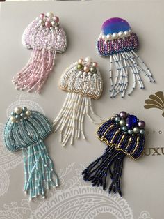 four different types of beaded brooches on a white sheet with intricate designs