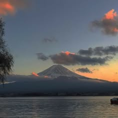 a boat floating on top of a body of water under a snow covered mountain in the distance