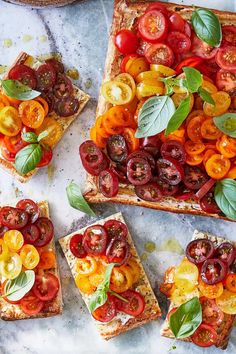 several slices of pizza with tomatoes and basil on top, sitting on a marble surface