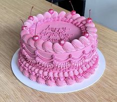 a pink birthday cake sitting on top of a wooden table