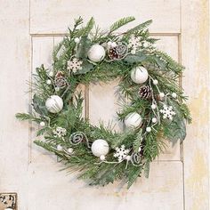 a christmas wreath hanging on the front door with pine cones and white balls around it