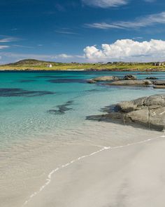 the water is crystal blue and clear with white sand on the beach near some rocks