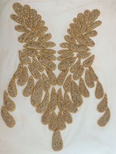 an elaborate gold necklace is displayed on a white surface