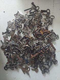 a pile of old keys sitting on top of a white table next to each other