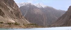 the mountains are covered in snow and have trees growing out of them, along with a body of water