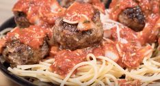 spaghetti and meatballs with sauce in a black bowl