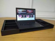 an open laptop computer sitting on top of a wooden table next to a black drawer